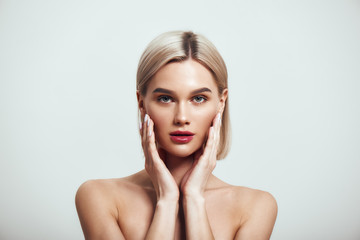 Confident in her beauty. Sexy young woman with blond hair and perfect shiny skin looking at camera...