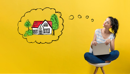 Dreaming of new home with young woman using a laptop computer