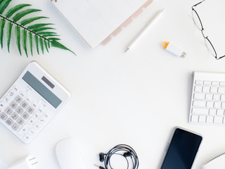 top view of office desk table with  calculator, notebook, plastic plant, smartphone and keyboard on white background, graphic designer, Creative Designer concept.