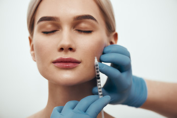 Wanna be perfect. Portrait of young pretty woman keeping eyes closed while doctors hand in blue...