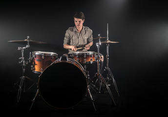 Fototapeta premium Professional drummer playing on drum set on stage on the black background