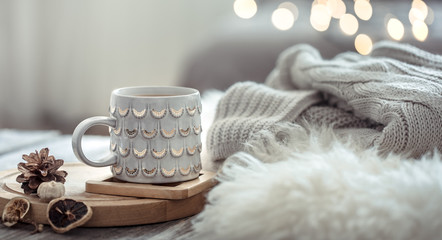 Coffee cup over Christmas lights bokeh in home on wooden table with sweater on a background and...