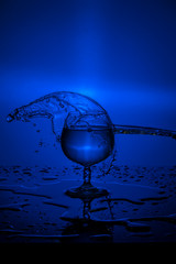 Splash of water in wine glass on a blue background
