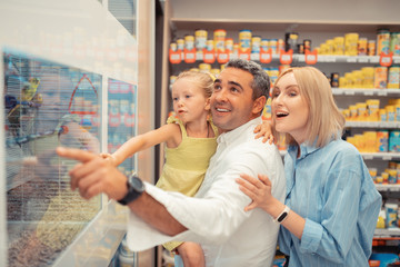 Obraz premium Blue-eyed girl feeling happy seeing parrots with parents