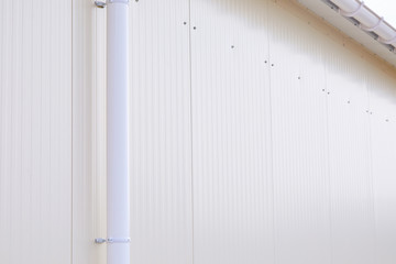 White plastic rain guttering system. Guttering drainage pipe exterior. Background of sandwich panel 