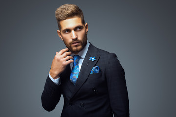 Naklejka premium Stylish young man in suit and tie. Business style. Fashionable image. Office worker. Sexy man standing and looking at the camera