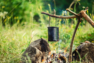 Cooking in sooty cauldron on campfire at forest