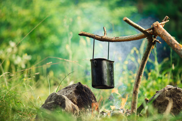 Cooking in sooty cauldron on campfire at forest