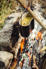 Cooking in sooty cauldron on campfire at forest