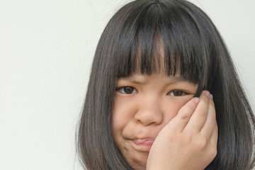 TMD and TMJ healthcare concept: Temporomandibular Joint and Muscle Disorder. Asia child kid girl hand on cheek face as suffering from facial pain, mumps or toothache