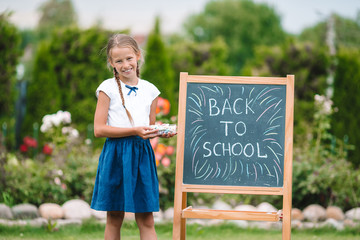 Happy little schoolgirl with a chalkboard outdoor