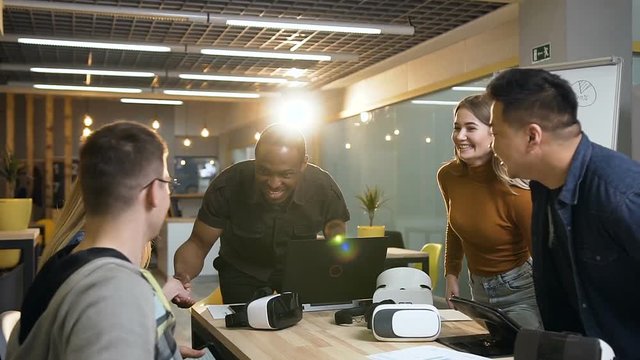 Team of hipster people greeting each other and sitting at the table.