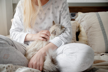 Blonde Giirl hygge with fluffy cat, pajama and blanket. Hugge and lagom concept comfort and simple life . Horizontal copyspace