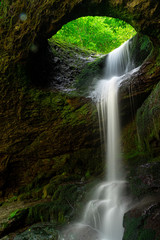Long exposure Murgul Deliklikaya waterfall over brown and green rocks.