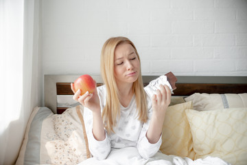 Woman on the diet craving to eat chocolate. Young woman holding  peace of chocolate in one hand and...