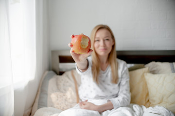 Obraz na płótnie Canvas Blonde Girl bites red apple. Health care and teeth care concept. Horizontal copyspace