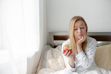 Blonde Girl bites red  apple. Health care and teeth care concept. Horizontal copyspace