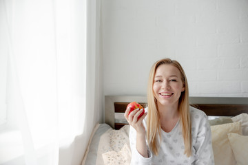 Blonde Girl bites red  apple. Health care and teeth care concept. Horizontal copyspace