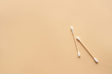 two bamboo cotton buds on beige background, space for text
