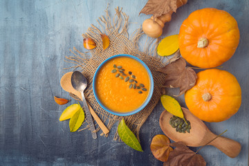 Pumpkin soup on rustic background. Autumn concept with pumpkin and fall leaves. Top view from above