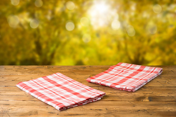 Empty wooden table with tablecloth over autumn nature park background