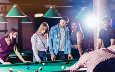 Young man playing in billiard. Posing near the table with a cue in his hands