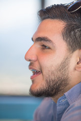 Obraz premium Close-up profile portrait of a young man. He is latin in his twenties and has a small casual beard. He is talking.