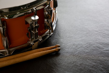 Drum and drum stick on black table background, top view, music concept