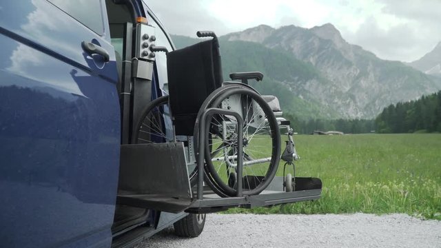 4k resolution video of electric lift specialized vehicle for people with disabilities. Empty wheelchair on a ramp with nature and mountains in the back. Self help for disabled people concept