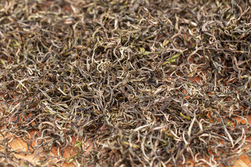 Premium Dry green tea leaves spread curing in bamboo basket tray after harvest