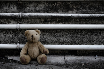 Teddy bear sitting in front of gray wall Feel lonely