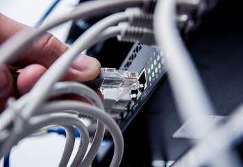 Technician connecting network cables to switches. Connecting cables in server cabinet.
