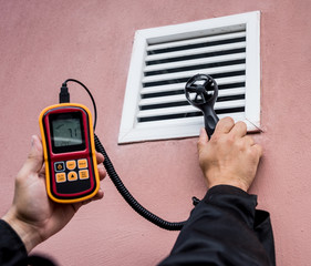 Technician use hand-held anemometer measuring air flowing measurement, wind speed and pressure.