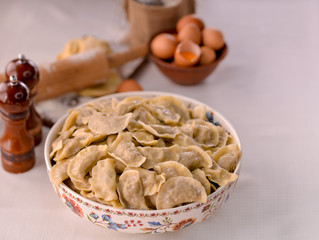 ready-made dumplings Ukrainian national dish in a painted dish on a board with ingredients of eggs and flour