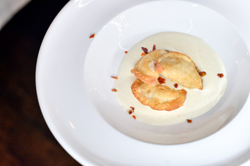 fried dumplings in cream sauce on a white plate