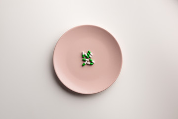 Medical capsules on a plate, isolated on white background. Flat lay.