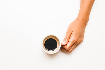 A hand with a cup of black coffee on a white background