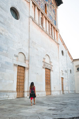 Fototapeta na wymiar A girl walking in front of a church in Lucca