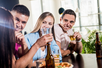 Cheerful friends in the pub. Drinking beer, wine and whisky, talking, having fun.