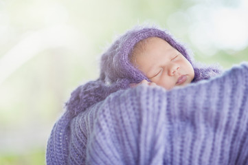 17 day old Smiling newborn baby is sleeping on his stomach in the basket on nature in the garden...
