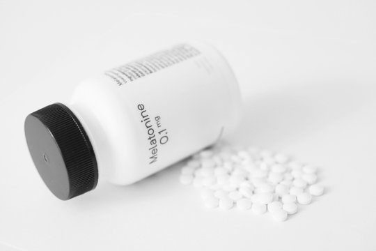 Melatonin insomnia medicine tablets and bottle with text Melatonin 0,1 mg. 