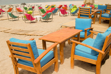 Fototapeta na wymiar Armchairs with soft pillows on the sandy shore. Rest zone