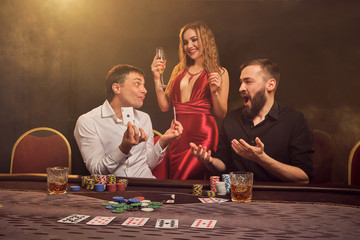 Group of a young wealthy friends are playing poker at a casino.