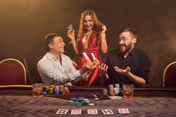 Group of a young wealthy friends are playing poker at a casino.