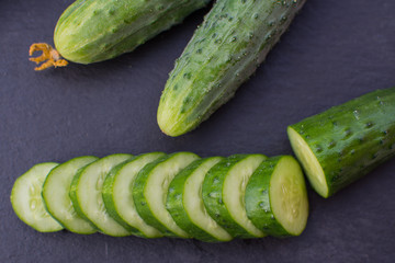 Sliced ​​fresh cucumber slices on a black stone board.