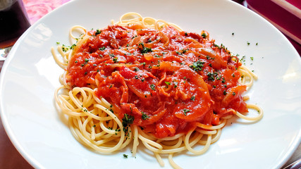 Fresh Italian spaghetti pasta with a spicy pepper and tomato sauce. Close up view on a white plate.
