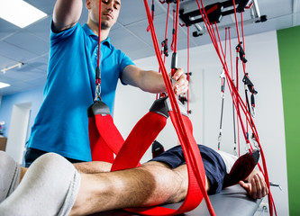 Physiotherapy. Suspension training therapy. Young man doing fitness traction therapy with suspension-based exercise training system.