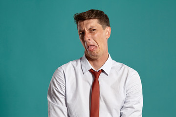 Portrait of a young brunet man posing in a studio against a blue background.