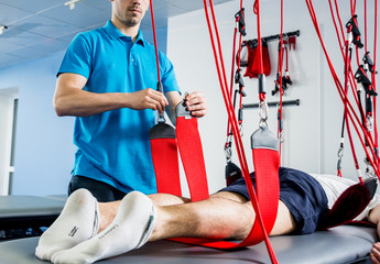 Physiotherapy. Suspension training therapy. Young man doing fitness traction therapy with...