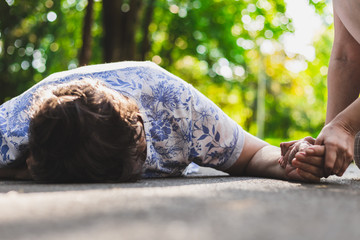 Old woman fell on the ground – Elder lying on the street while a citizen is trying to help her